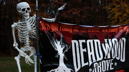 A decorative skeleton stands next to a banner advertising Deadwood Grove Haunted Forest.