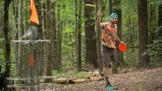 A young man enjoys playing disc golf.
