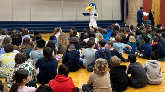 Elementary students listen to a reading of Harry the Heron children's book.