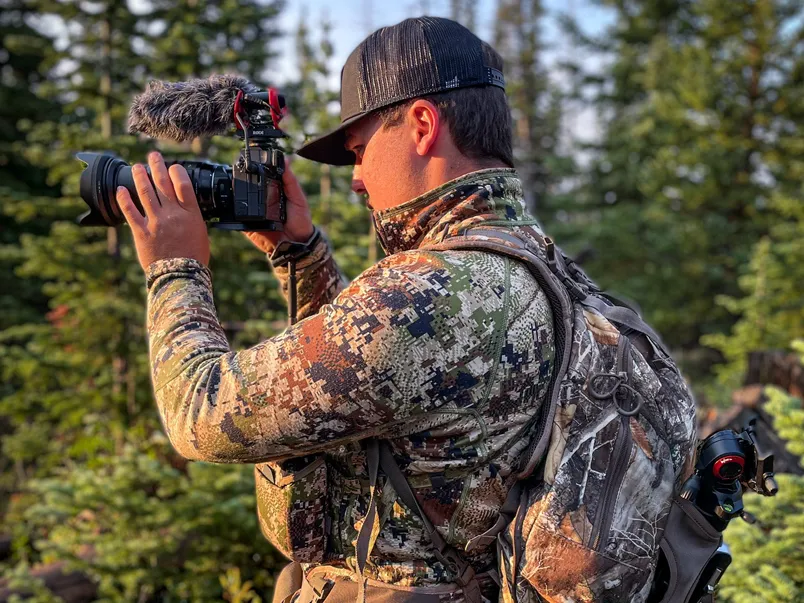 Student in hunting gear capturing the action on camera.