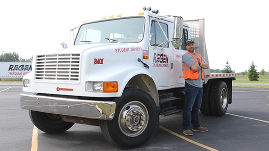 CDL-B student stand in front of training truck