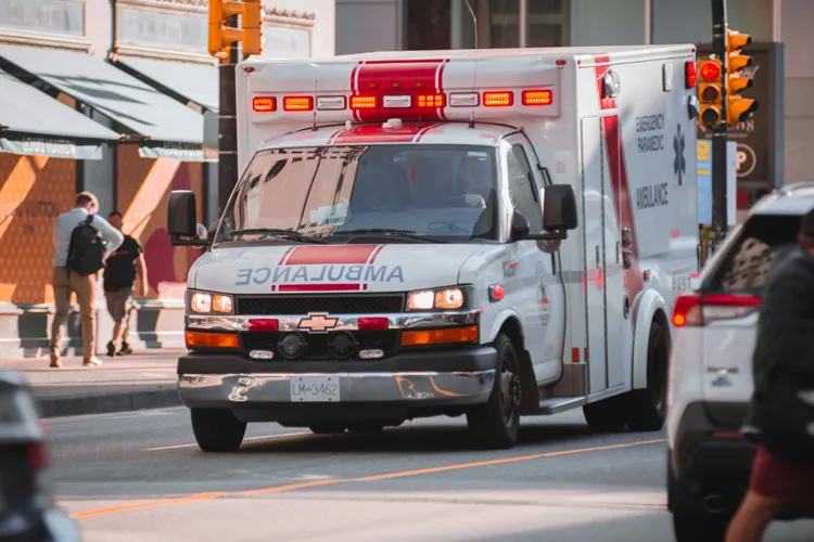 Ambulance drives down a busy street.