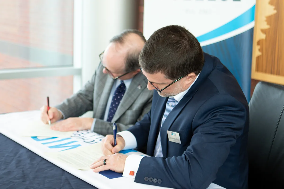 Two college representatives signing an agreement