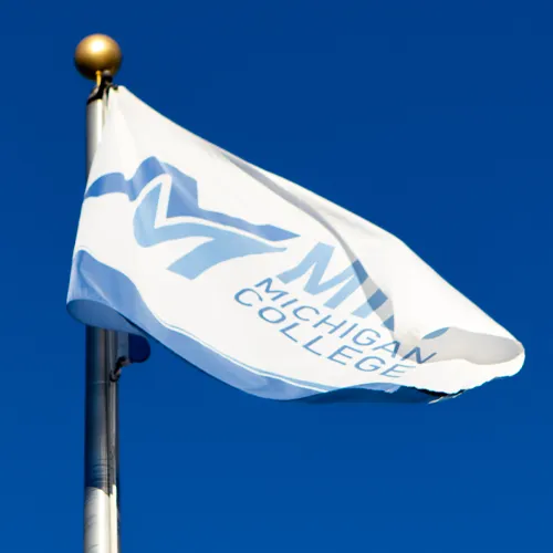 Mid Michigan College flag against a blue sky.