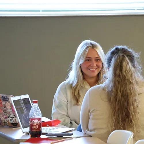 Two students chatting in a classroom.